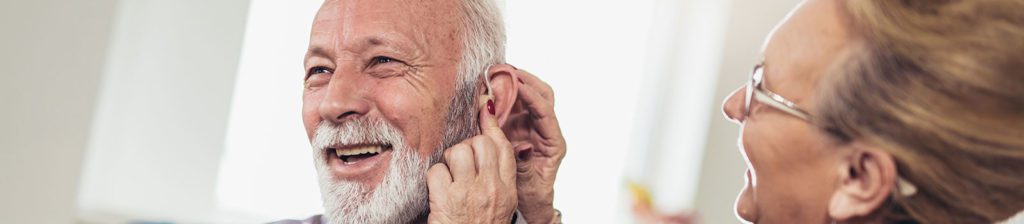 an elderly man with hearing aids getting adjusted