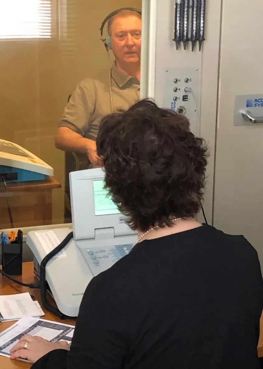 An Associated Audiologists care provider during a patient exam with medical equipment.