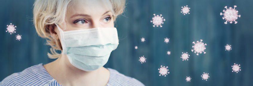 young woman in medical face protection mask indoors on blue background. Sick person