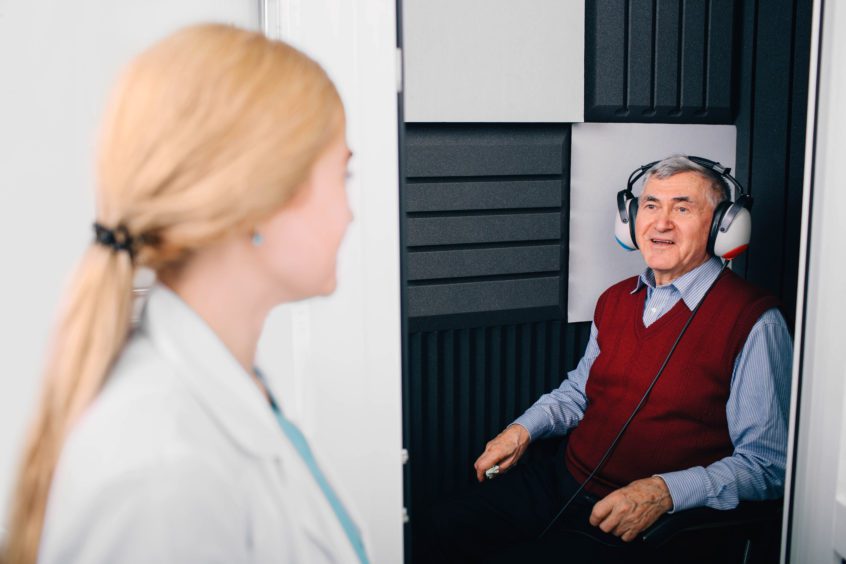 senior patient having hearing exam in special audio room