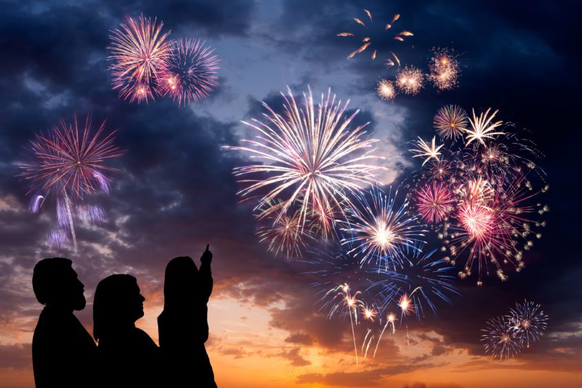 man, woman, and little girl look at holiday fireworks