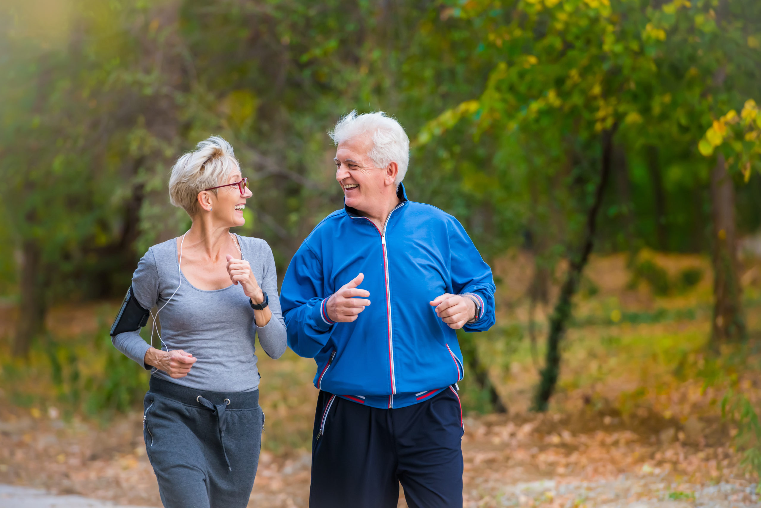 Smiling senior active couple jogging together in the park