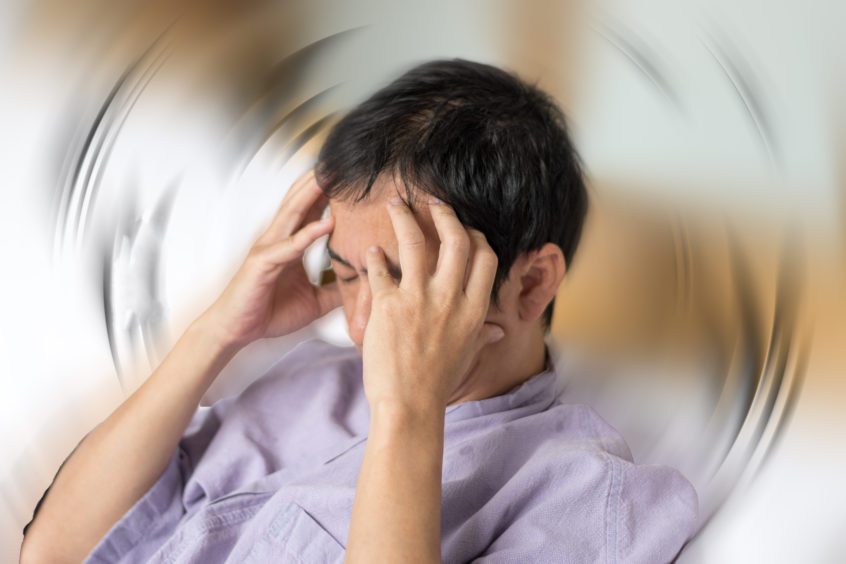 man in purple shirt holding his head