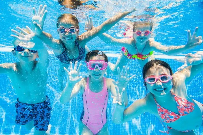 Group of children posing for a photo underwater in a pool.