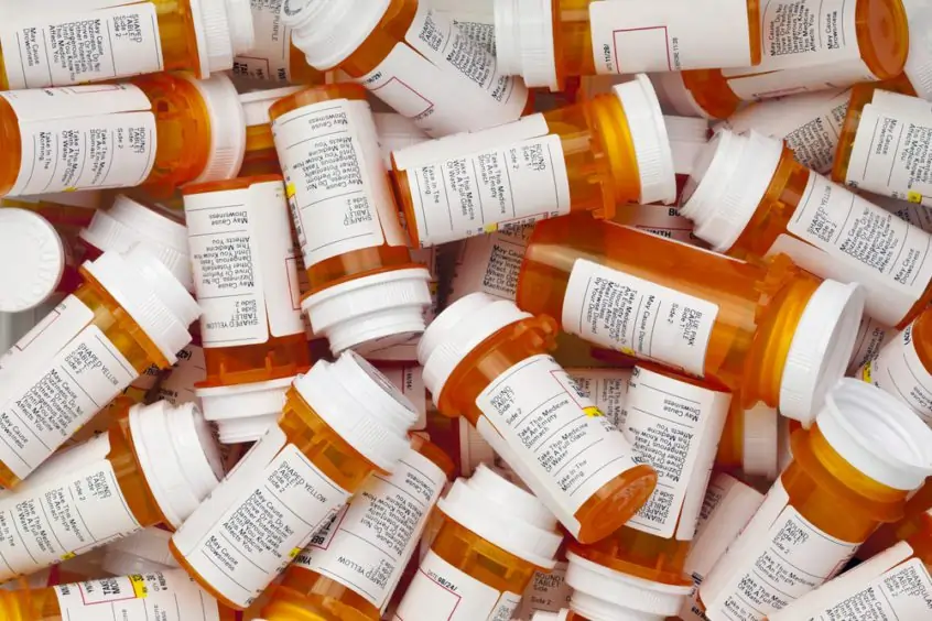A collection of similar, orange prescription bottles pile together.