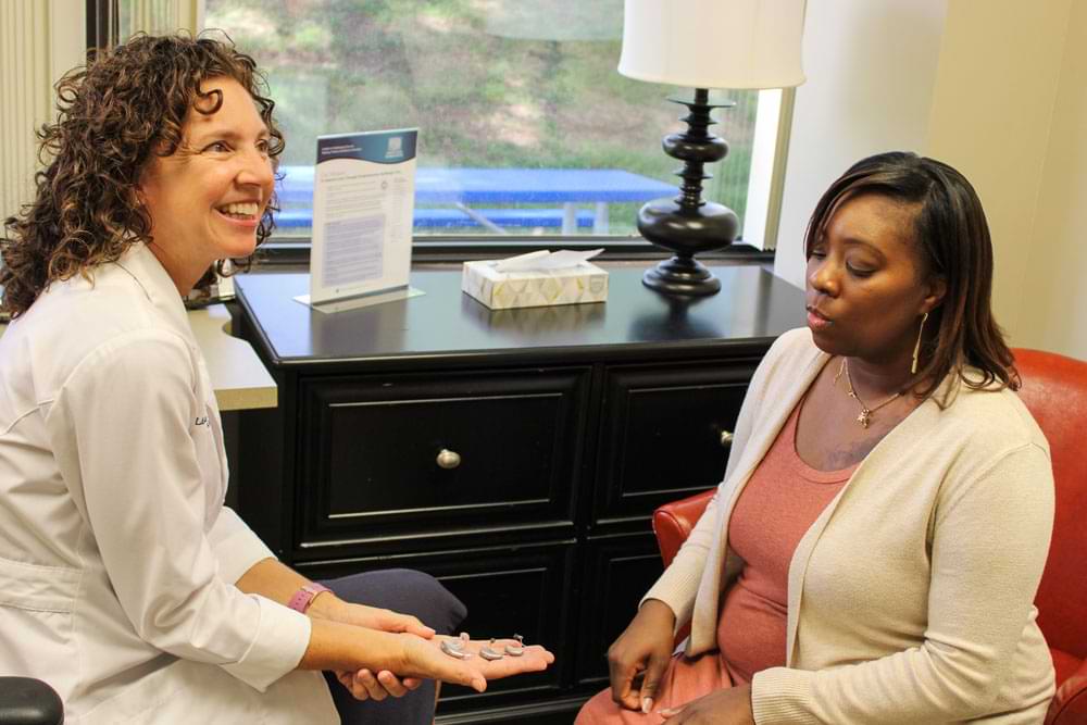 Lisa Battani, AuD, CCC-A at Associated Audiologists showing hearing aid options to a patient