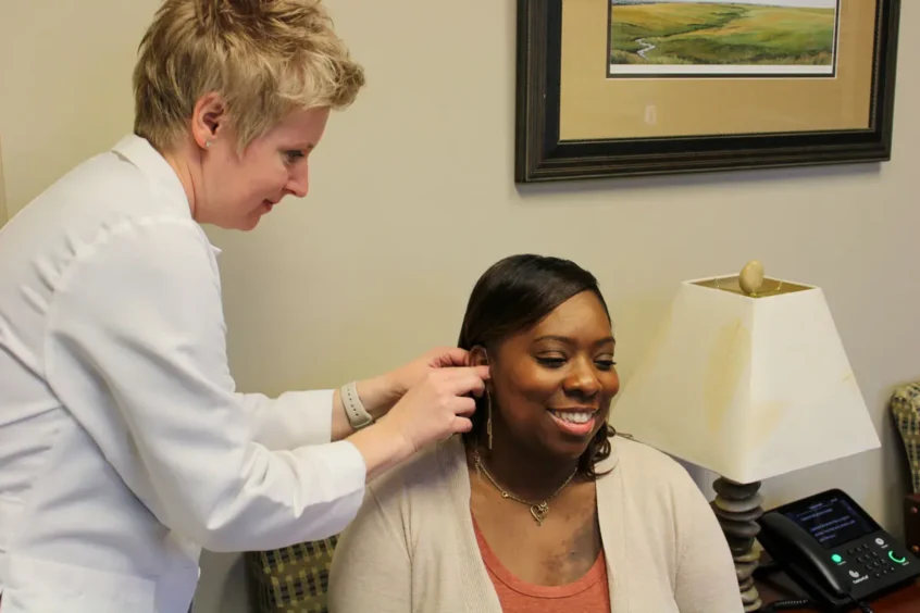 Susan Smittkamp, Au.D., Ph.D. fitting a hearing aid on a patient at Associated Audiologists in Shawnee Mission
